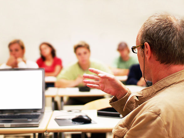 An instructor presenting to a classroom, laptop open on the desk
