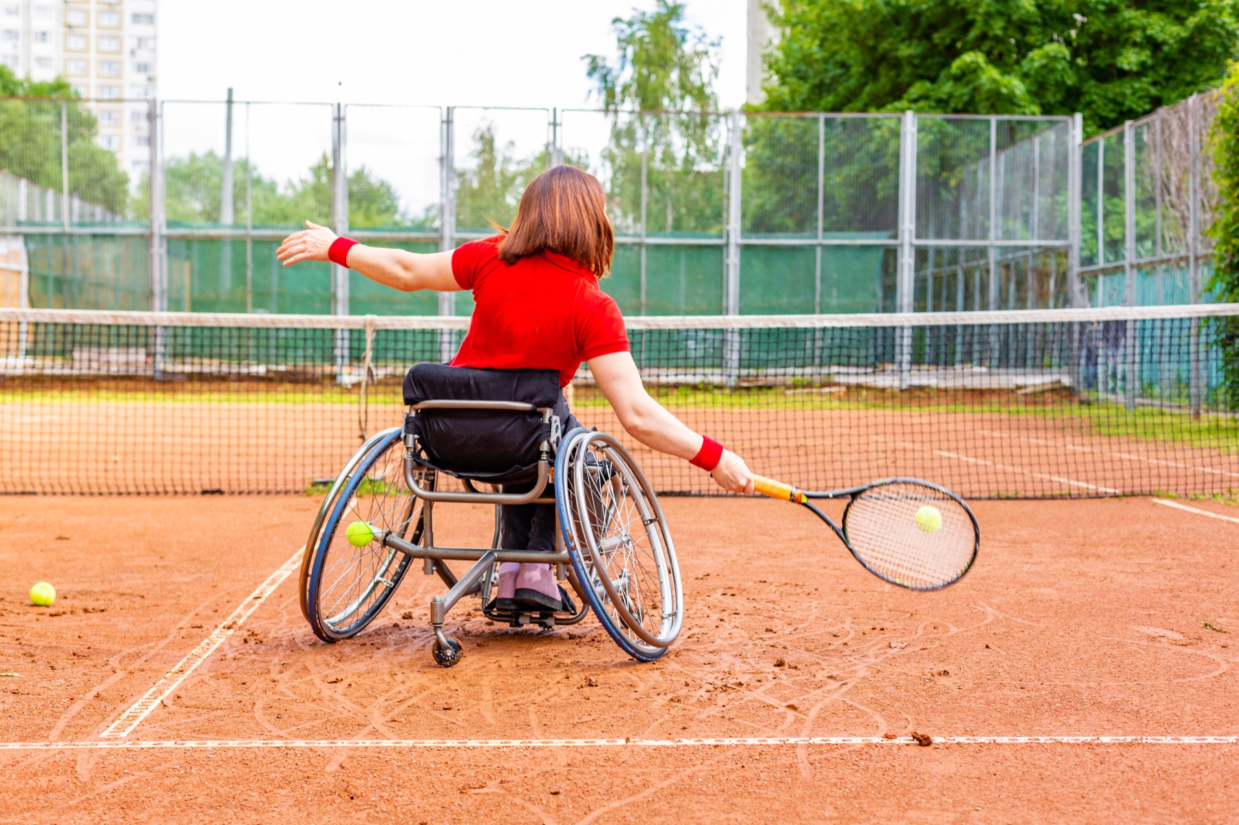 Adaptive tennis athlete in a sports wheelchair on a clay court