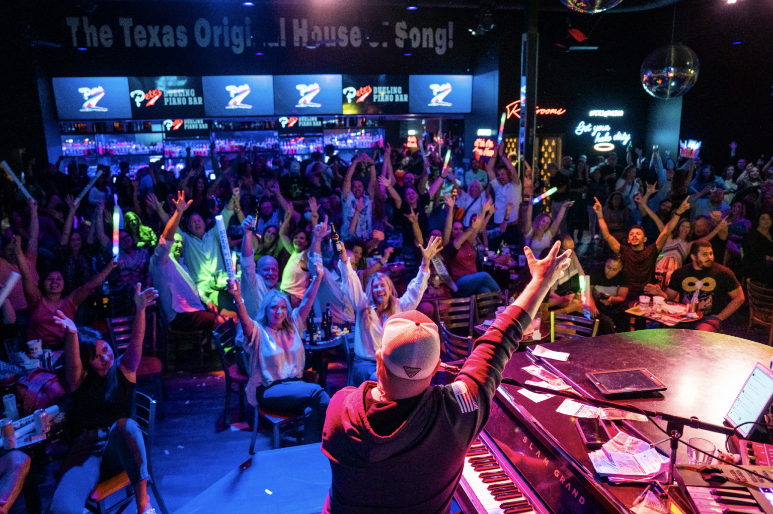 Crowd at an APTA Geriatrics gathering, arms raised during a live performance