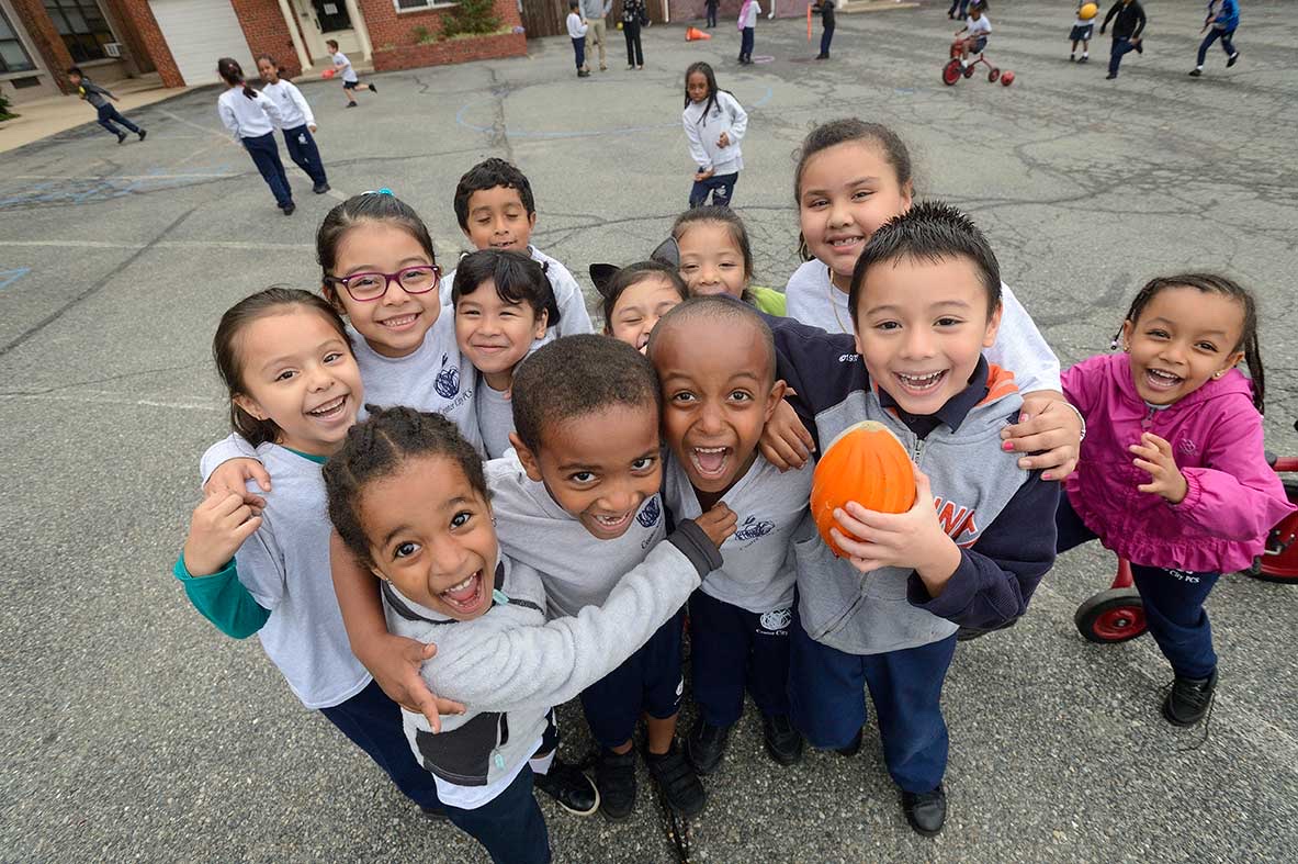 Center City PCS students in uniform huddled together, laughing on the playground